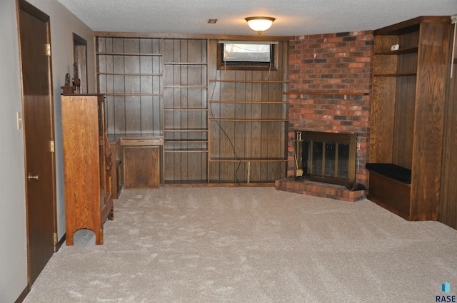 unfurnished living room with light carpet, a textured ceiling, a brick fireplace, and wood walls