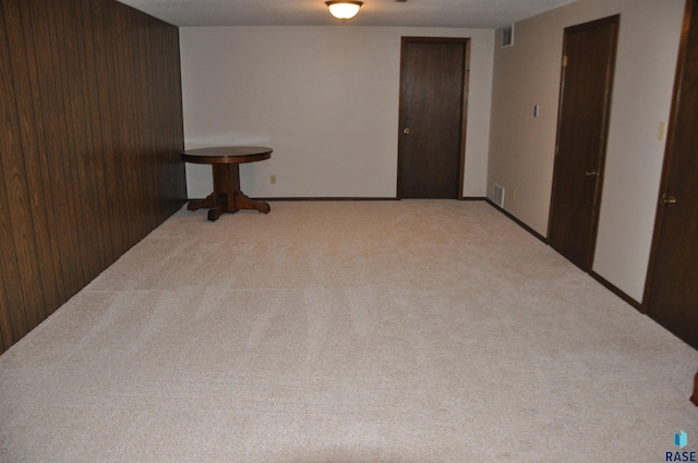 carpeted empty room with wood walls