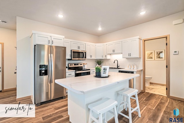 kitchen with a breakfast bar, white cabinets, decorative backsplash, a kitchen island, and stainless steel appliances