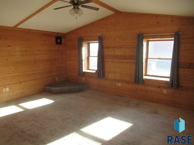 unfurnished room with lofted ceiling with beams, wood walls, and ceiling fan