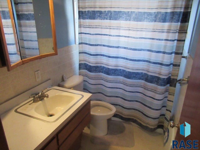 bathroom with a shower with curtain, vanity, tile walls, and toilet