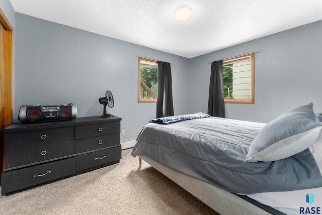 carpeted bedroom featuring baseboard heating and a textured ceiling