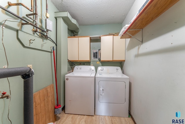 washroom with cabinets, light wood-type flooring, a textured ceiling, wooden walls, and separate washer and dryer