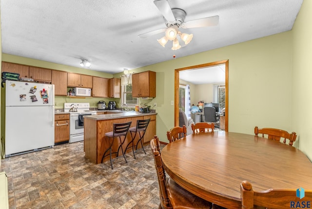 kitchen featuring kitchen peninsula, white appliances, plenty of natural light, and ceiling fan