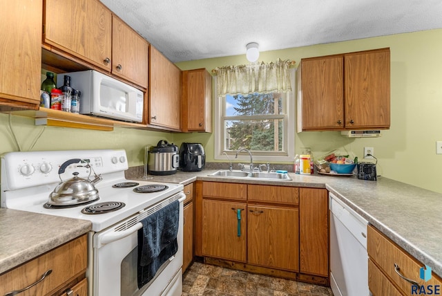 kitchen featuring a textured ceiling, white appliances, and sink