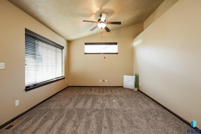 carpeted spare room with ceiling fan, plenty of natural light, and vaulted ceiling