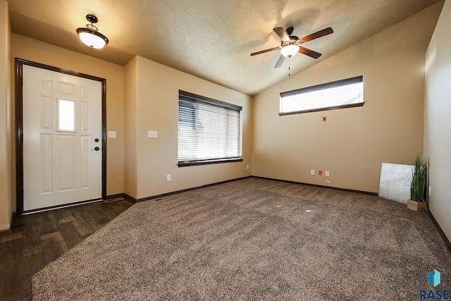 carpeted entrance foyer with a textured ceiling, ceiling fan, and vaulted ceiling