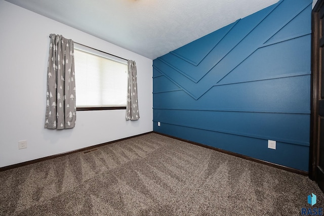 carpeted spare room featuring a textured ceiling and lofted ceiling