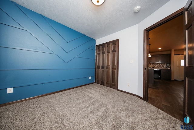 unfurnished bedroom featuring dark carpet, a textured ceiling, and a closet