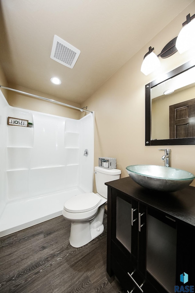 bathroom featuring hardwood / wood-style floors, vanity, toilet, and walk in shower