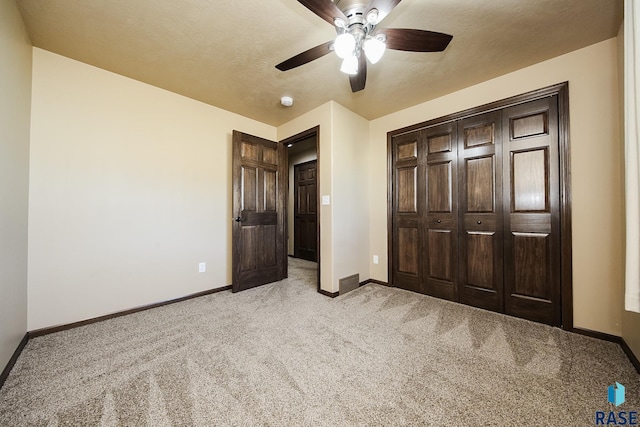 unfurnished bedroom featuring light carpet, a closet, and ceiling fan