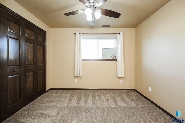 unfurnished bedroom featuring ceiling fan, light carpet, and a closet