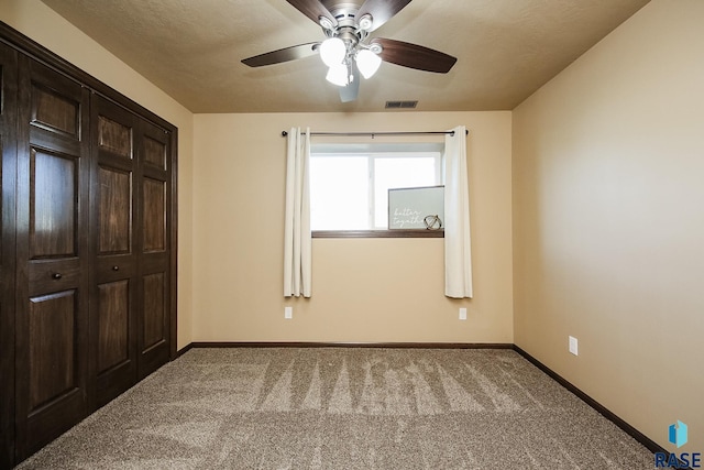 unfurnished bedroom featuring ceiling fan, a closet, and light colored carpet