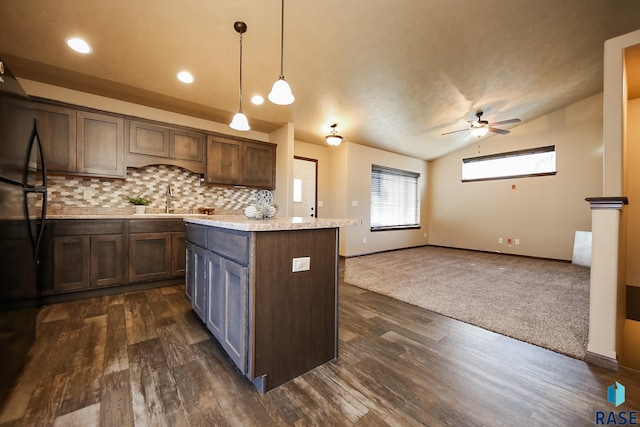 kitchen with dark brown cabinetry, a center island, hanging light fixtures, backsplash, and lofted ceiling