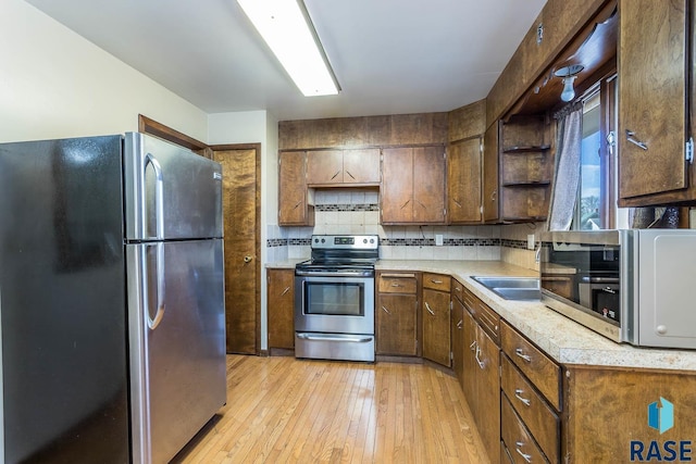 kitchen with backsplash, stainless steel appliances, and light hardwood / wood-style flooring