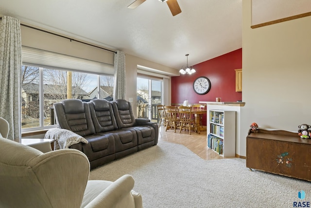 living room featuring ceiling fan with notable chandelier, light colored carpet, and vaulted ceiling