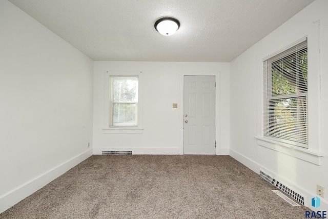 unfurnished room featuring a textured ceiling and carpet floors