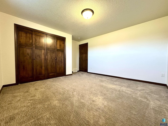 unfurnished bedroom featuring a textured ceiling, a closet, and carpet