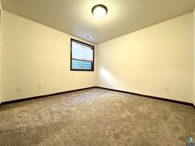 empty room with carpet floors and a textured ceiling