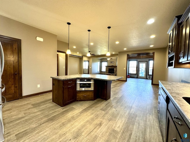 kitchen featuring dark brown cabinets, a kitchen island, ceiling fan, and pendant lighting