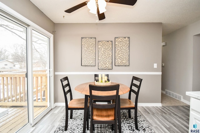 dining space with ceiling fan and light wood-type flooring