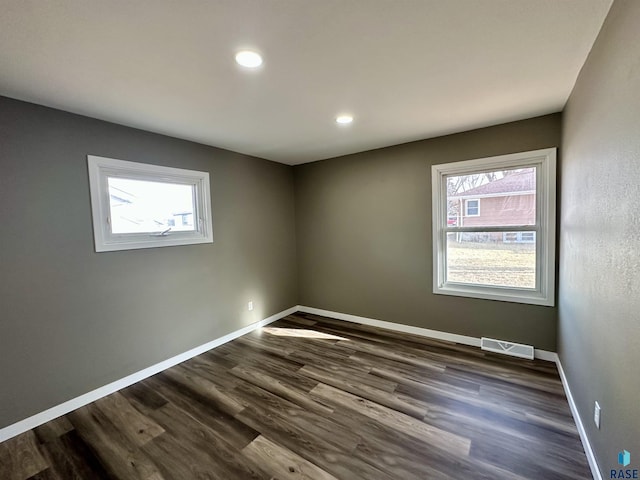 unfurnished room with dark hardwood / wood-style flooring and a wealth of natural light