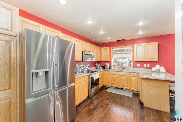 kitchen featuring sink, light stone counters, dark hardwood / wood-style floors, decorative light fixtures, and appliances with stainless steel finishes