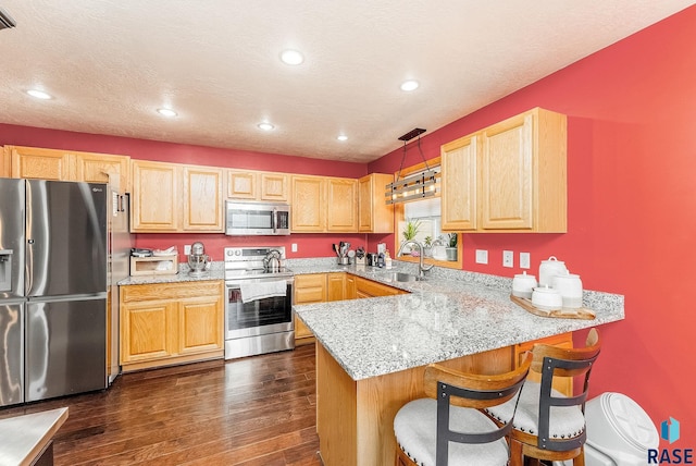 kitchen with kitchen peninsula, pendant lighting, stainless steel appliances, and dark wood-type flooring