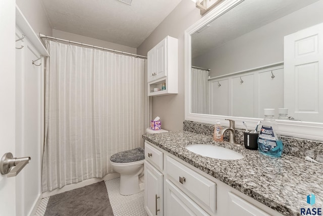 bathroom featuring tile patterned flooring, vanity, toilet, and a textured ceiling