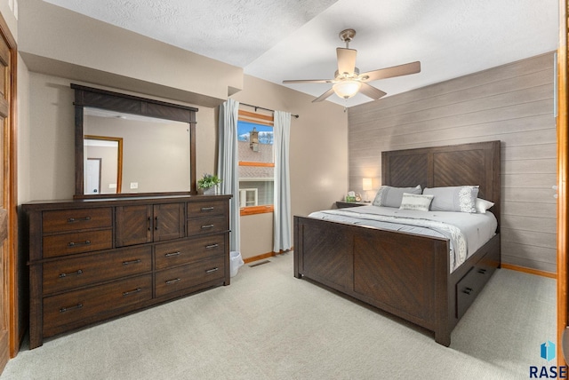 carpeted bedroom featuring a textured ceiling, ceiling fan, and wood walls