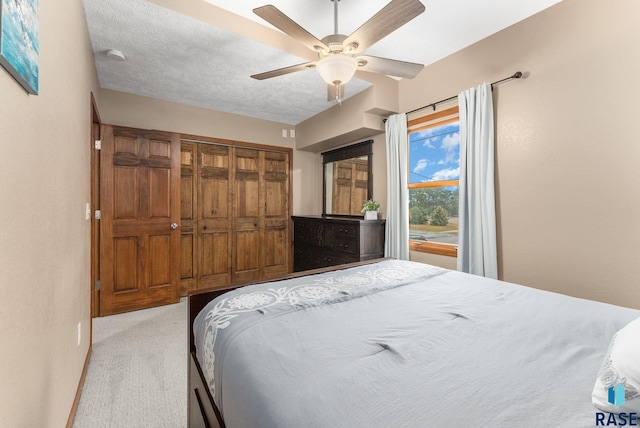 carpeted bedroom with ceiling fan, a closet, and a textured ceiling