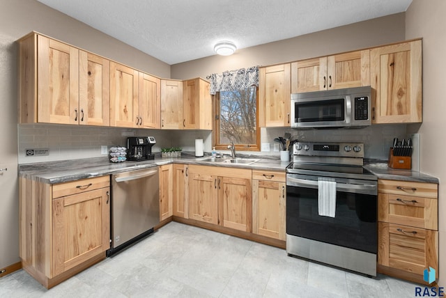 kitchen featuring sink, light brown cabinets, a textured ceiling, decorative backsplash, and appliances with stainless steel finishes