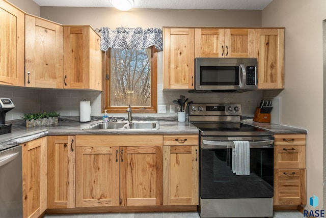 kitchen with light brown cabinetry, backsplash, appliances with stainless steel finishes, and a sink