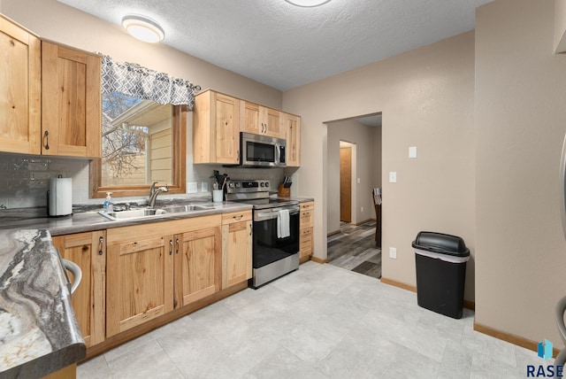 kitchen featuring a textured ceiling, stainless steel appliances, backsplash, and sink