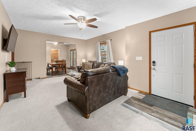 living room with ceiling fan, light colored carpet, and a textured ceiling