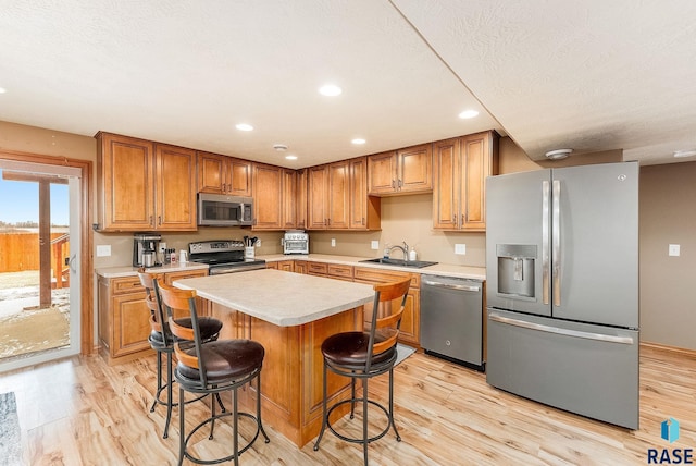 kitchen featuring a kitchen breakfast bar, stainless steel appliances, sink, a center island, and light hardwood / wood-style floors