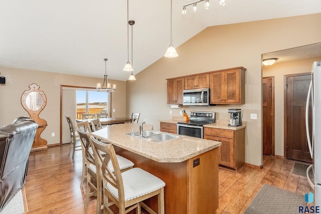 kitchen with an inviting chandelier, sink, hanging light fixtures, an island with sink, and stainless steel appliances