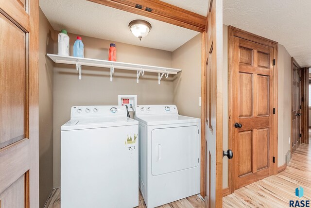 laundry area featuring light hardwood / wood-style flooring, a textured ceiling, and independent washer and dryer