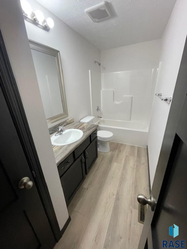 full bathroom with shower / bath combination, wood-type flooring, a textured ceiling, toilet, and vanity