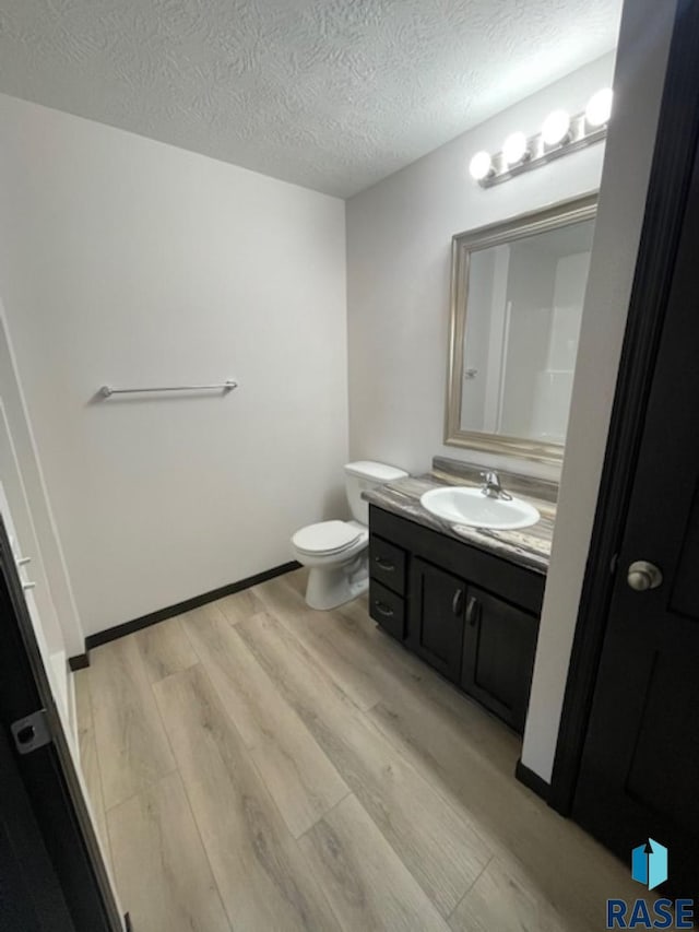 bathroom featuring hardwood / wood-style flooring, vanity, toilet, and a textured ceiling