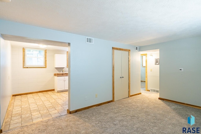 carpeted empty room featuring a textured ceiling