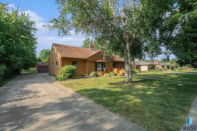 single story home with a garage, a front lawn, and an outdoor structure