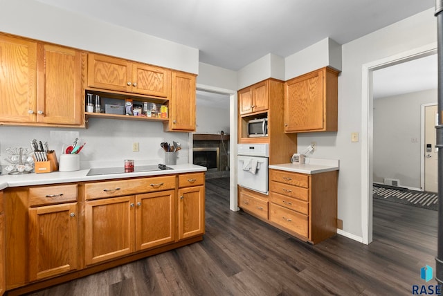 kitchen featuring dark hardwood / wood-style flooring, black electric cooktop, oven, and stainless steel microwave