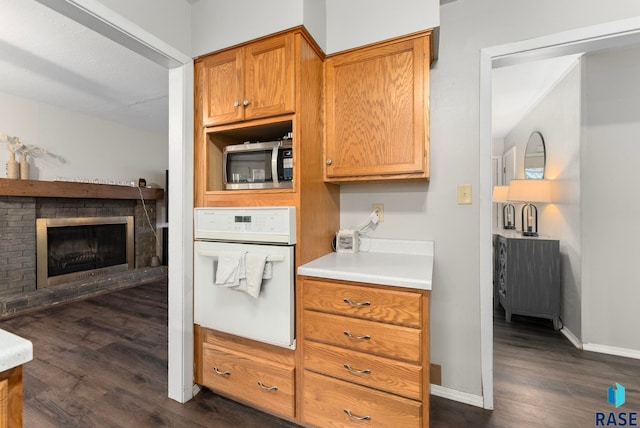 kitchen with white oven, a fireplace, and dark hardwood / wood-style floors