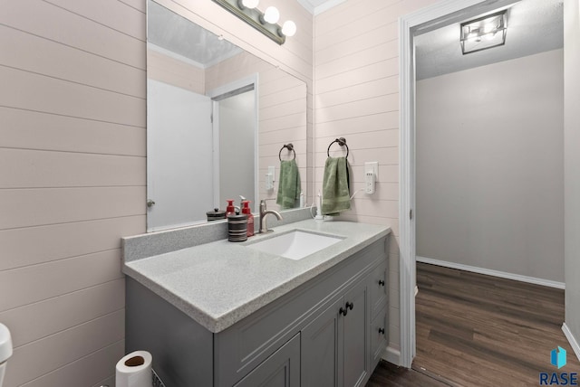 bathroom featuring hardwood / wood-style floors, vanity, and wood walls