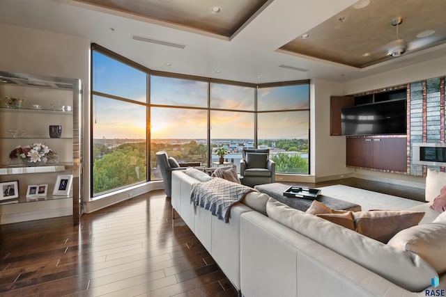 living room featuring a healthy amount of sunlight, floor to ceiling windows, and a tray ceiling