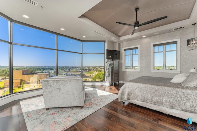 bedroom featuring floor to ceiling windows, a tray ceiling, ceiling fan, and hardwood / wood-style flooring