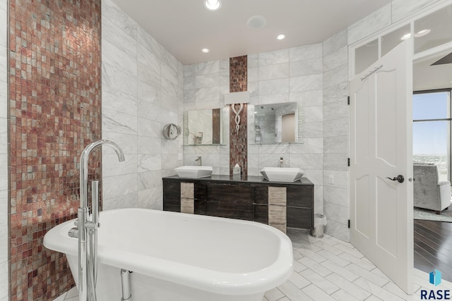 bathroom featuring tile patterned floors, a washtub, vanity, and tile walls