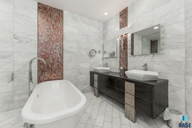 bathroom featuring a washtub, vanity, and tile walls