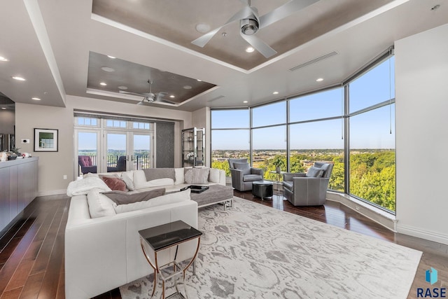 living room with dark hardwood / wood-style floors, french doors, and a tray ceiling